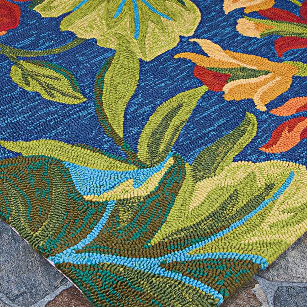 A zoomed-in corner of the Couristan Covington Indoor/Outdoor Rug - Tropical Orchid/Azure-Forest Green-Red displays bright green leaves and orange blooms against an azure background