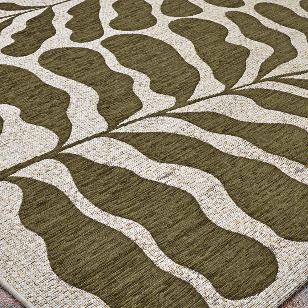 A zoomed-in section of the Couristan Castille Indoor/Outdoor Rug - Fiore/Tea Leaf showcases its symmetrical, organic leaf-like design in tea leaf green and beige