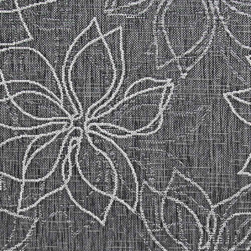 A zoomed-in section of the Couristan Charm Indoor/Outdoor Rug - Botanical/Ash clearly shows the intricate white floral design against a dark ash weave