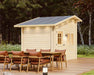 Back corner of the Sawmill Structures Bluewater Den 67 Garden Room, highlighting its clean wood finish and tall roof behind a dining table
