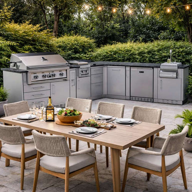 Backyard dining setup features the Sunstone Savanna 16ft Outdoor Cabinet Package with 60° Angle behind a table, surrounded by greenery and string lights
