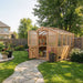 Backyard garden scene with a stone path leads to the 8x8 Outdoor Living Today Western Red Cedar Greenhouse Kit