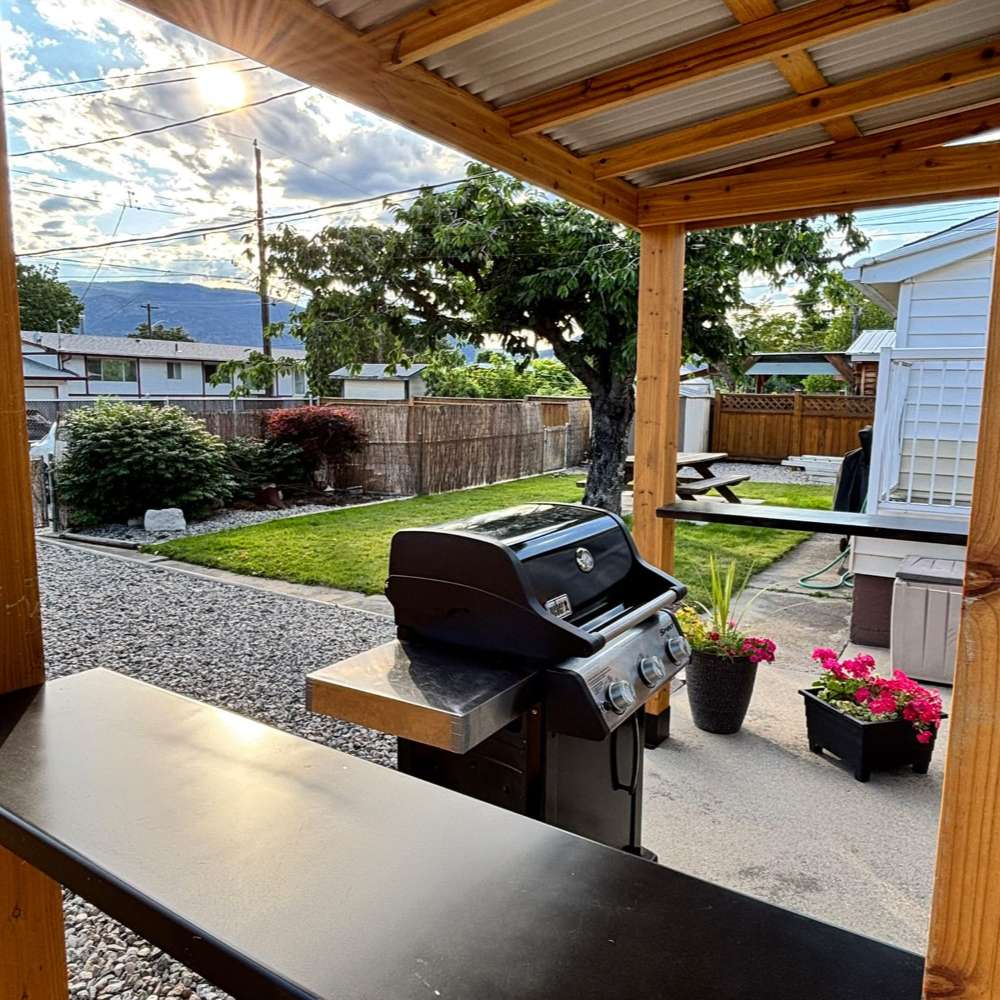 Barbecue grill sits under Outdoor Living Today Western Red Cedar 8x5 Grill Gazebo, providing shaded outdoor cooking on a concrete patio