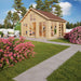 A cozy wooden cabin with large windows and a gable roof stands in a blooming garden, representing the GardenHouse24 USA Bern 70 Garden Room