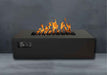 Black Warming Trends AON Steel Rectangular Fire Pit Table displays vivid flames rising from the burner against a dark stone background