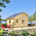 Front view of the lakeside BlueWater Bungalow 160 with a gable roof, wooden deck, red Adirondack chairs, and outdoor dining furniture.