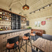 Rustic BlueWater Bungalow 160 bar interior with a studded counter, leather stools and sofa, liquor shelving, and vaulted pine ceiling.