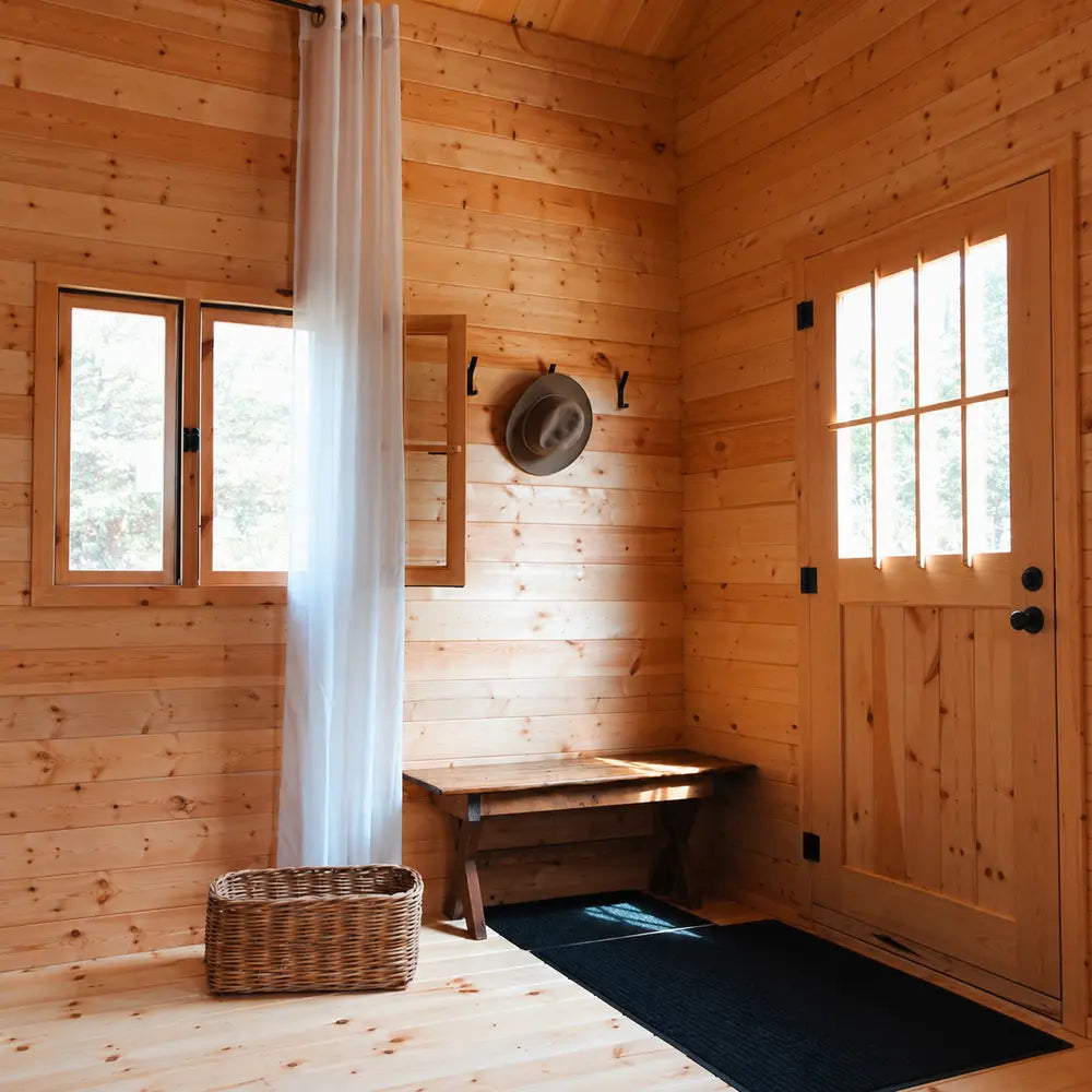wooden entryway in the BlueWater Loft 160 38mm with a rustic bench, hat rack, wicker basket, curtain, and paneled door.