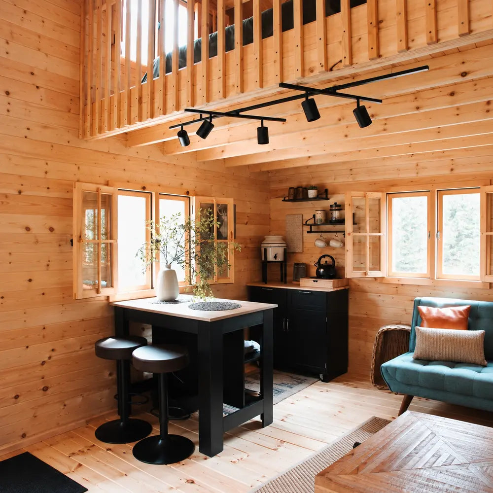 Rustic kitchen and dining area in the BlueWater Loft 160 38mm with a black island, barstools, open shelving, and teal seating.
