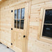 Close-up of the Bluewater Den 67 wooden door and adjacent window highlighting the pale wood grain and sturdy black hardware.