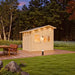 Bluewater Den 67 at dusk with warm light glowing through its door and windows beside a landscaped lawn and forest.