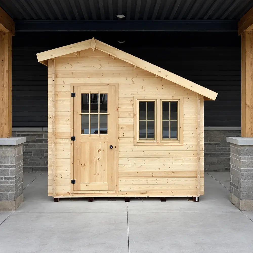 Straight-on view of the Bluewater Den 67 showing its asymmetrical sloped roof, windowed wooden door and two narrow front windows.