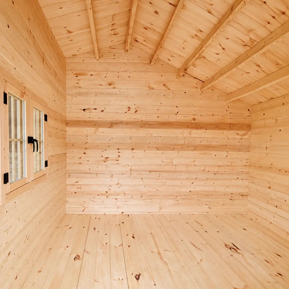 Empty Bluewater Den 67 interior with natural pine walls, matching flooring, a high pitched ceiling and exposed wooden rafters.