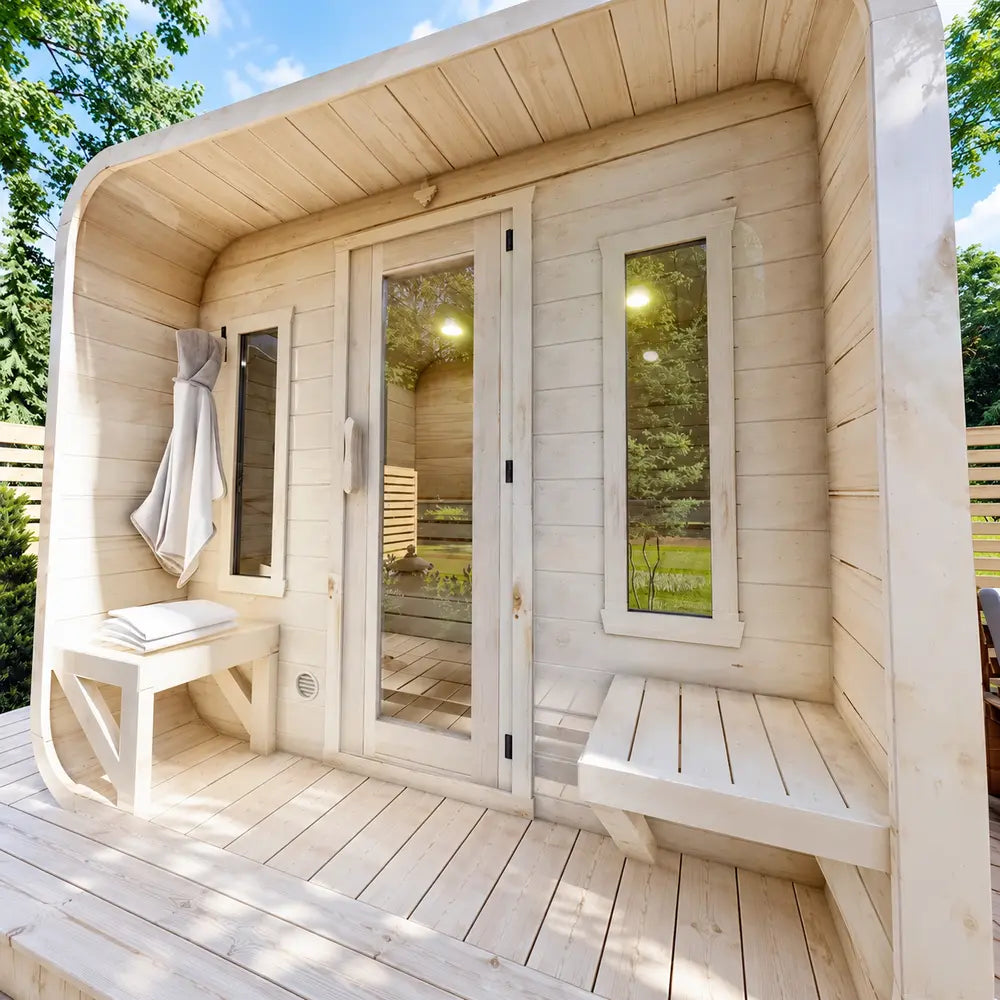 Close-up of the Sawmill Structures Box Sauna entrance with a glass door, two narrow windows, wooden benches, towel hook, and folded towels.