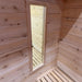 Tall narrow wood-framed window beside a slatted corner bench and pale horizontal wall paneling inside the Sawmill Structures Box Sauna.