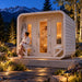 Box Sauna outdoor sauna illuminated on a clear Colorado night, with warm interior lighting, two adults relaxing after a sauna session, and snow-dusted mountains in the distance.