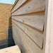 Close side view of the Sawmill Structures Box Sauna highlighting its overlapping pale wooden exterior panels, natural grain, and weather-resistant construction.