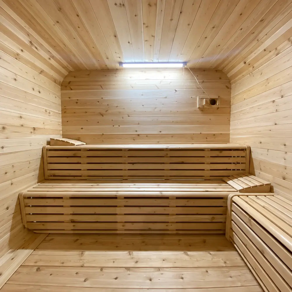 Warm Sawmill Structures Box Sauna interior with smooth pine walls, bright overhead lighting, and two-tier slatted wooden bench seating.
