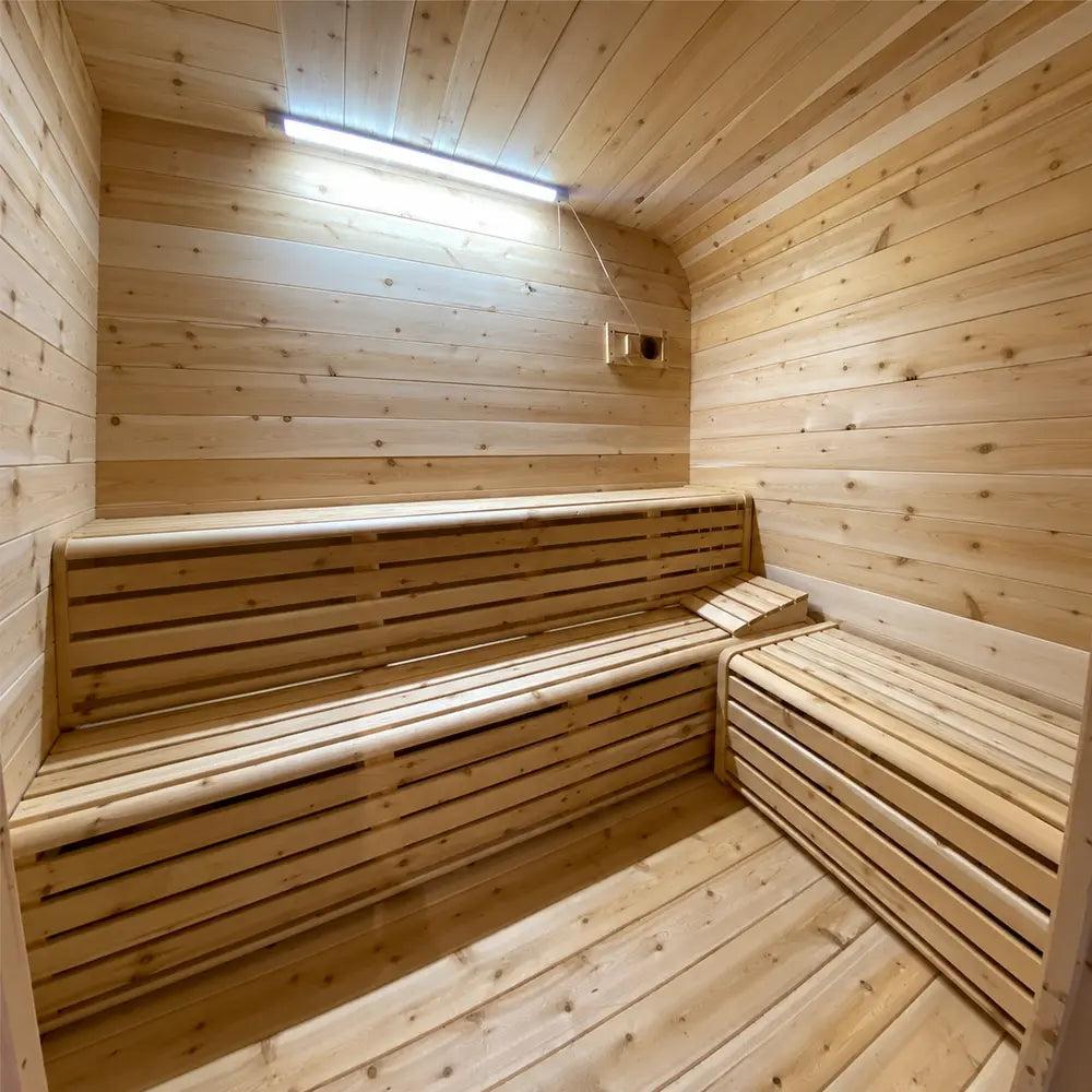 Interior of the Sawmill Structures Box Sauna featuring pale wood paneling and two-tier slatted benches wrapping around the corner.