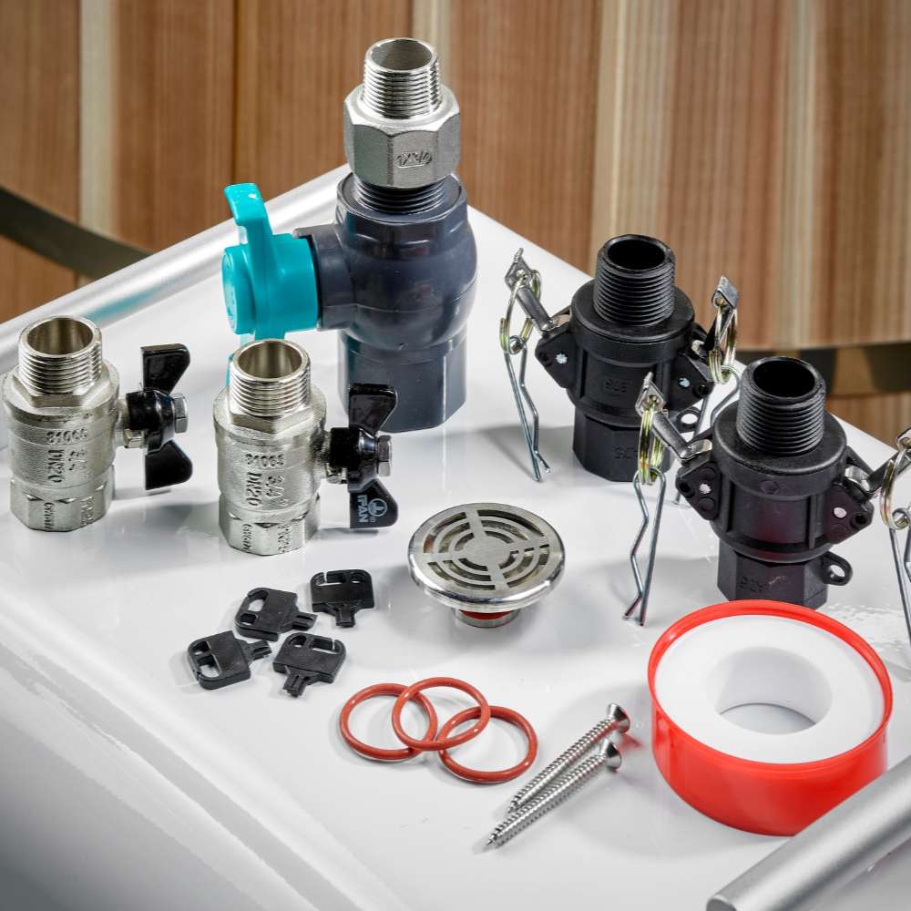 Brass and gray valves, black hose connectors, a drain grate, red O-rings and thread seal tape for Golden Designs Dynamic Cold Therapy Cuboid 304 Nano-Coated Stainless Steel Cold Plunge Tub XL lie on a white surface