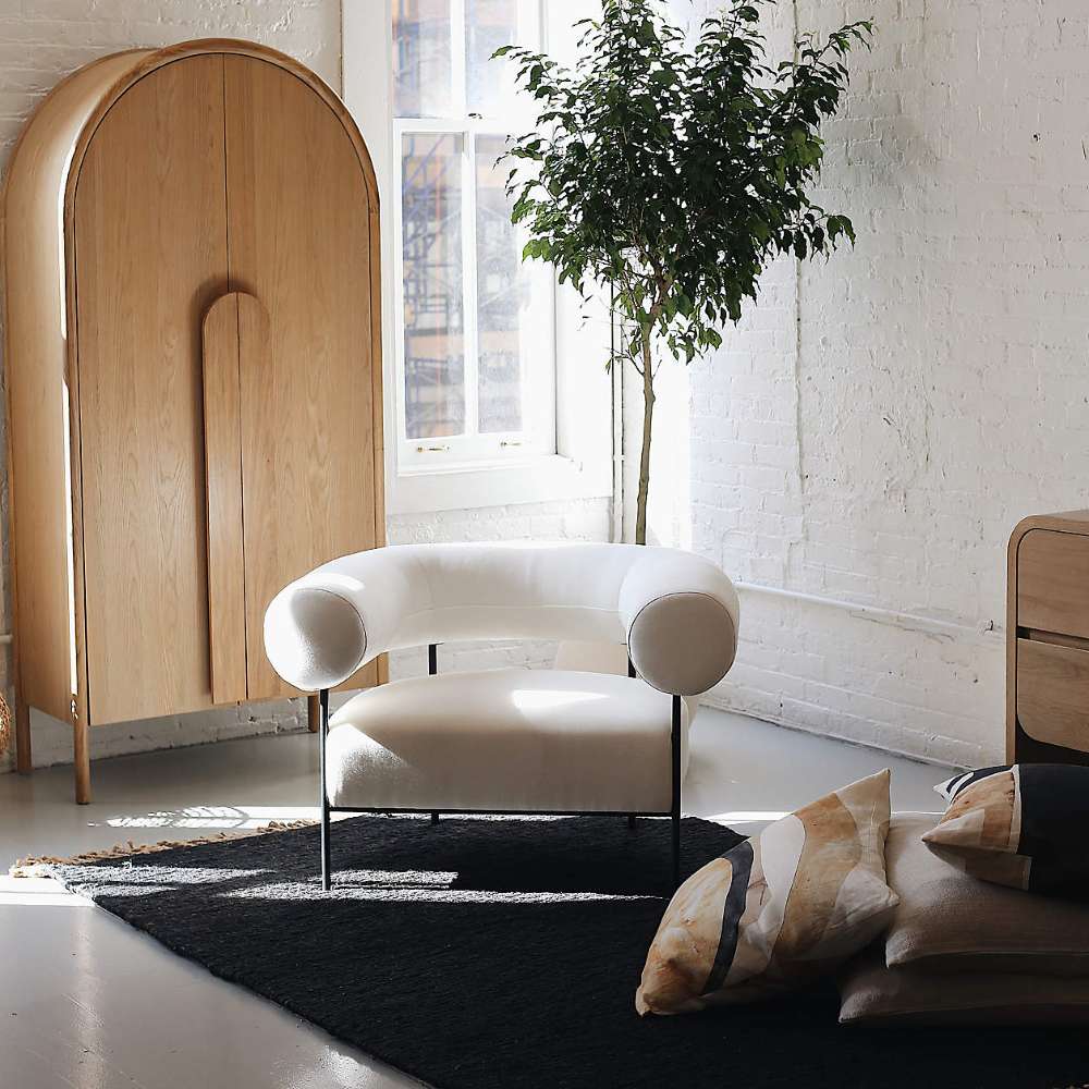 Bright living room featuring Crate & Barrel Annie 38" Natural Storage Cabinet paired with a curved lounge chair and indoor tree