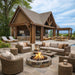 Brookside Timber Frame Denalivue Pavilion outdoor living space with timber pavilion, kitchen, dining area, wicker seating, and central fire pit