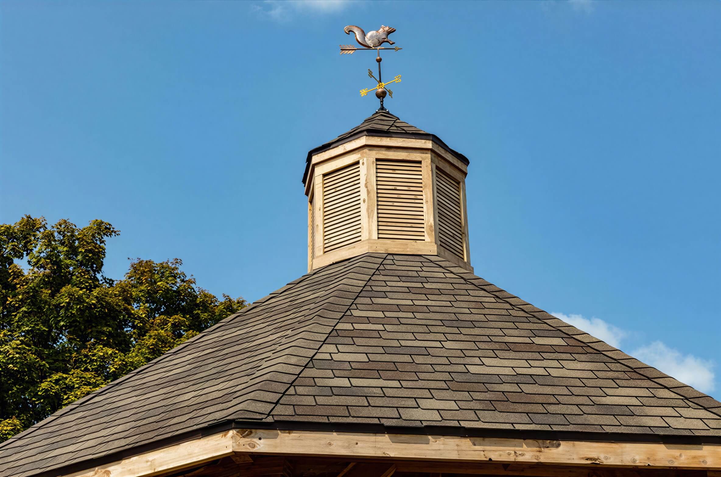 Brookside Timber Frame Lakeside Majestic Pavilion roof peak with cupola and weather vane against blue sky