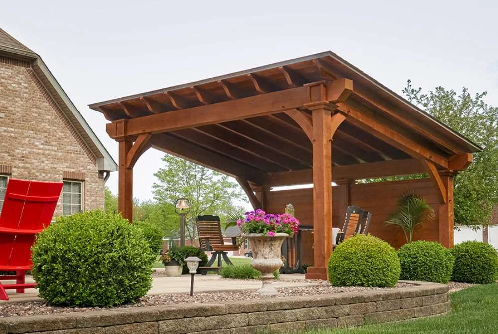 Brookside Timber Frame Glazier Hideaway Pavilion displays expert craftsmanship with its wooden beams, adding rustic charm to the stylish outdoor setting