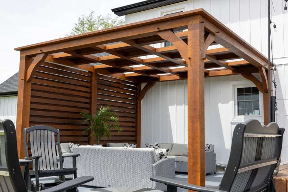 Brookside Timber Frame Timber Resort Pergola creates an inviting shaded lounge area with a partial privacy wall