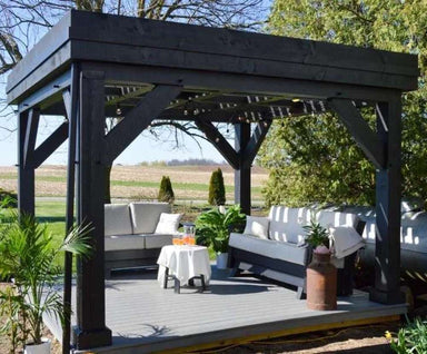 Brookside Timber Frame Zion Resort Pergola is elegantly set up with an outdoor sectional, table, and plants