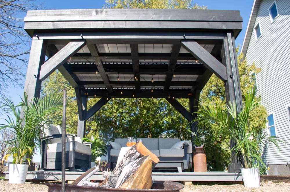 Brookside Timber Frame Zion Resort Pergola provides a cozy, shaded lounge space with a seating area, plants, and a fire pit nearby