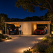 Brightly illuminated Carport Hans 70 at night in California with two vehicles and adults arriving home with their bags.