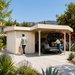 Carport Kampen 44 in a sunny San Diego garden as two adults unload groceries from a vehicle parked beneath the wooden canopy.