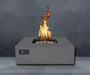 Charcoal Warming Trends AON Steel Square Fire Pit Table is shown with flames rising high against a dark wall backdrop