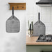 Chicago Brick Oven 12x15 Perforated Pizza Peel neatly hanging on a kitchen wall and countertop