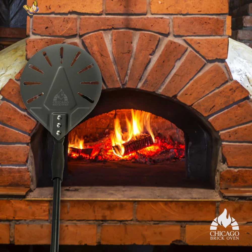 Chicago Brick Oven 7 Diameter Turning Perforated Pizza Peel in front of a lit brick oven