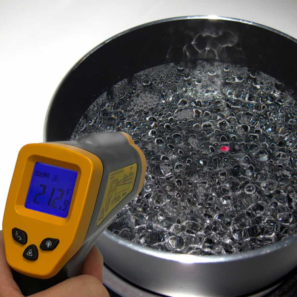 Chicago Brick Oven Infrared Thermometer Gun in use, aimed at boiling water, with a temperature reading visible on the screen