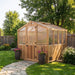 Close front view displays the 8x8 Outdoor Living Today Western Red Cedar Greenhouse Kit with potted plants on each side