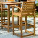 Close outdoor view shows Westminster Teak Somerset Teak Bar Stool next to a round table with a bowl of oranges, set on a patio with water in the background