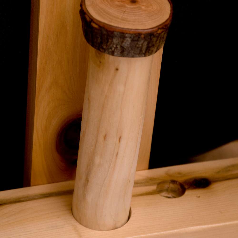 Close-up image shows Fireside Lodge Voyageur Futon with a smooth cylindrical wooden peg inserted into the frame, showing its handcrafted construction