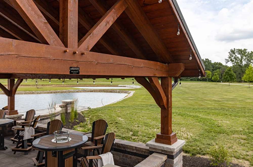 Close-up of Brookside Timber Frame Combolan Estate Pavilion highlights the detailed wooden beams, rustic charm, and warm lighting under the gabled roof