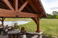 Close-up of Brookside Timber Frame Combolan Estate Pavilion highlights the detailed wooden beams, rustic charm, and warm lighting under the gabled roof