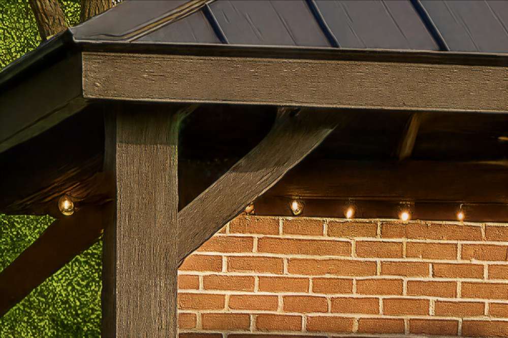 Close-up of Brookside Timber Frame Stonewood Pavilion highlights its sturdy wooden post, angled support beams, and string lights beneath the roof