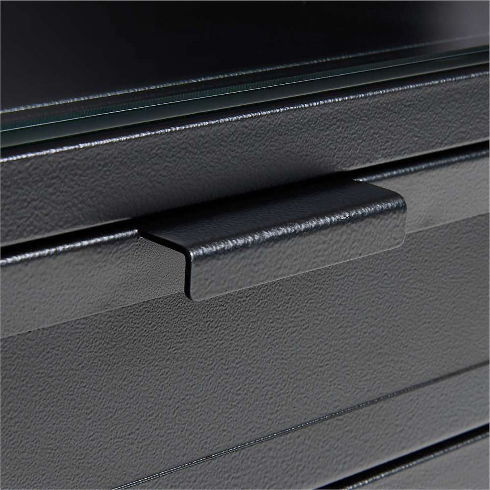 Close-up of Crate & Barrel Casement 60" Black Metal Desk featuring a textured black metal drawer handle and glass top edge