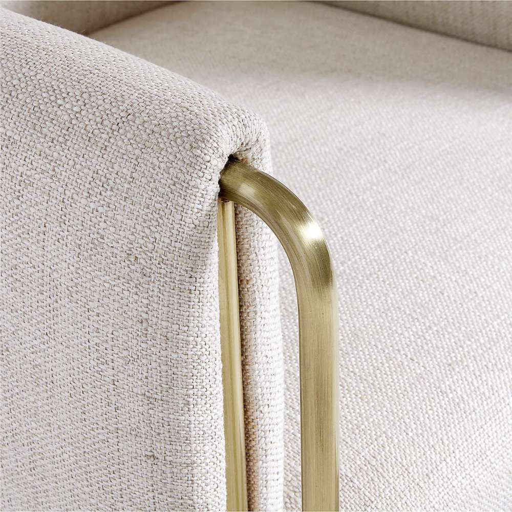 Close-up of Crate & Barrel Caterina Natural Upholstered Office Chair with Brass Base, highlighting the textured natural fabric and brushed brass arm frame