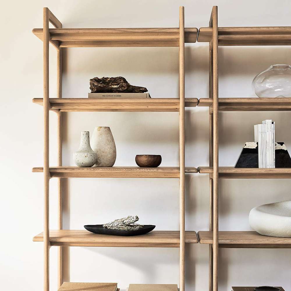 Close-up of Crate & Barrel Elias Natural Elm Wood Open Bookcase displaying decorative vases, books, and bowls on its smooth natural wood shelves