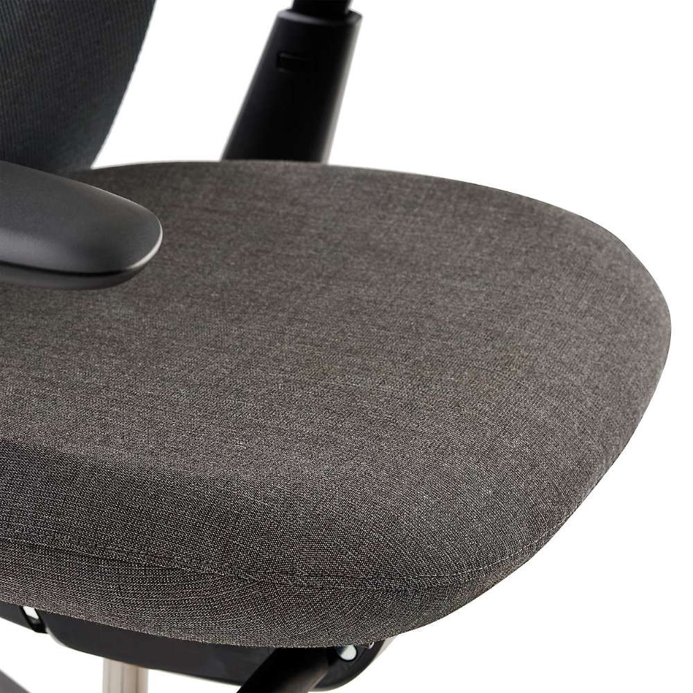 Close-up of Crate & Barrel Haworth Soji Upholstered Charcoal and Mesh Office Chair shows the cushioned charcoal upholstered seat with a smooth rounded edge