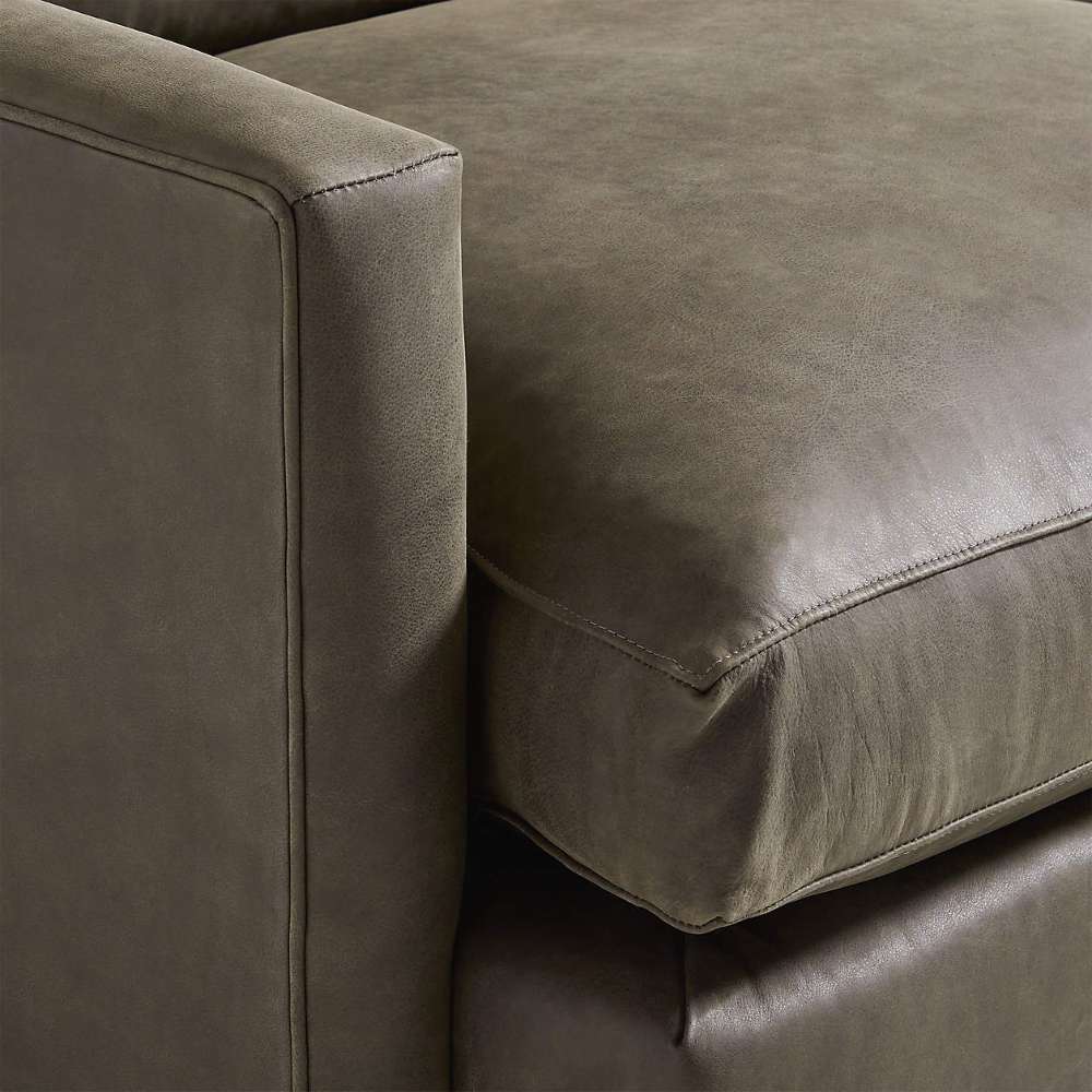 Close-up of Crate & Barrel Lounge Sofa showing the smooth gray leather upholstery, plush seat cushion, and clean track arm detail
