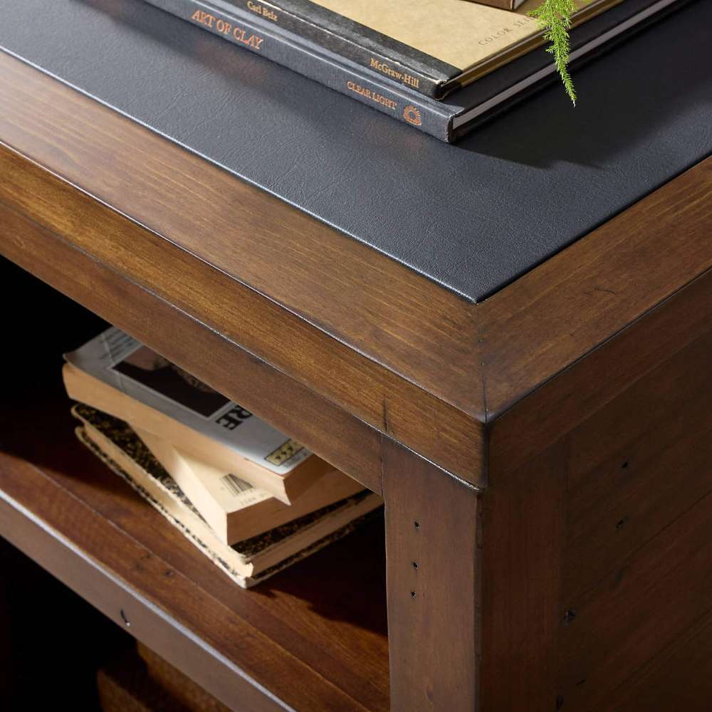 Close-up of Crate & Barrel Morris 72" Chocolate Brown Writing Desk showing its wood frame, black inset desktop, and open storage shelf
