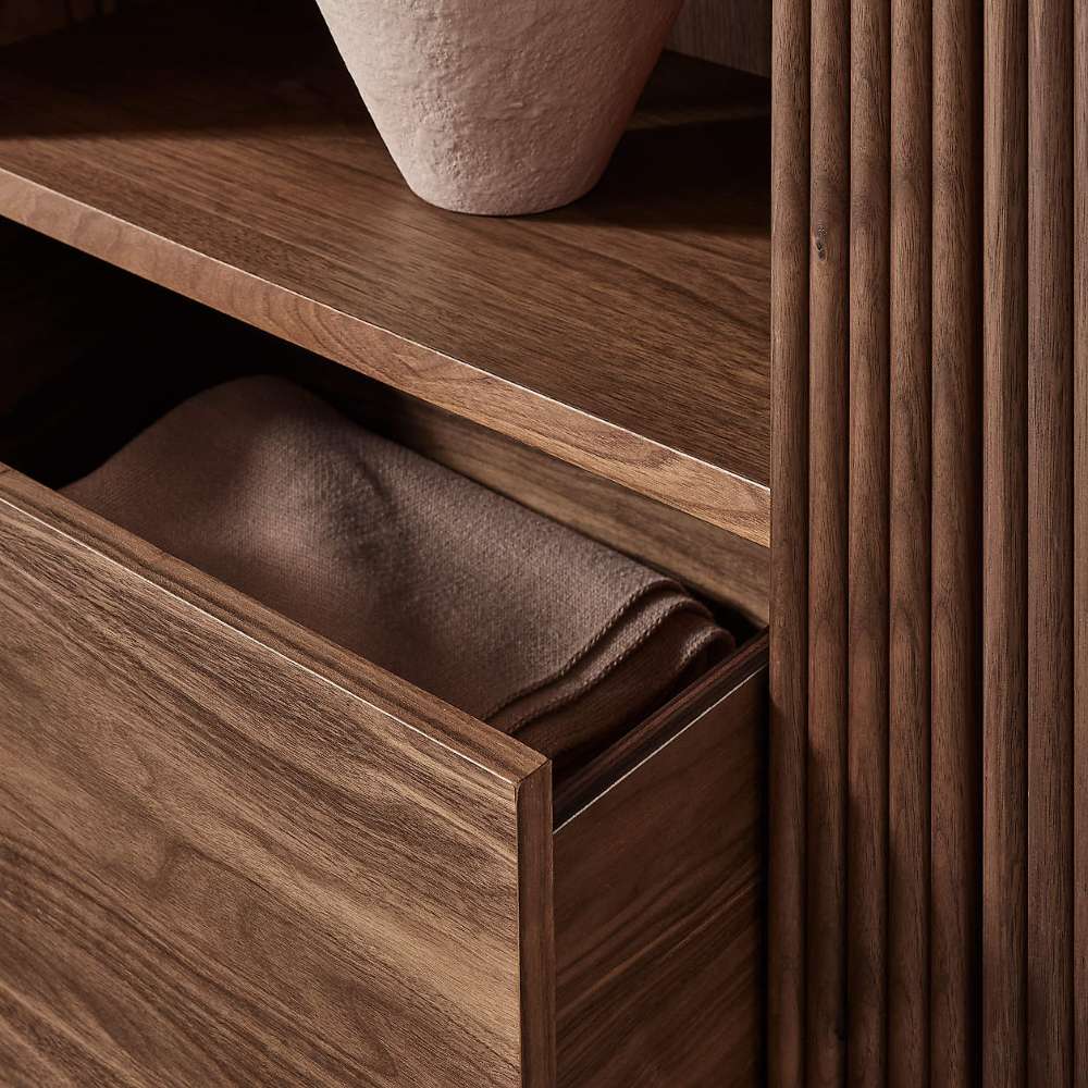 Close-up of Crate & Barrel Siena 34" Walnut Wood 4-Shelf Storage Bookcase with Drawer highlighting the open drawer and fluted wood detail